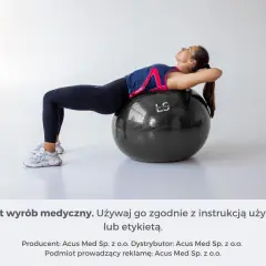Kobieta ćwiczy na czarnej piłce gimnastycznej, opierając na niej plecy.
